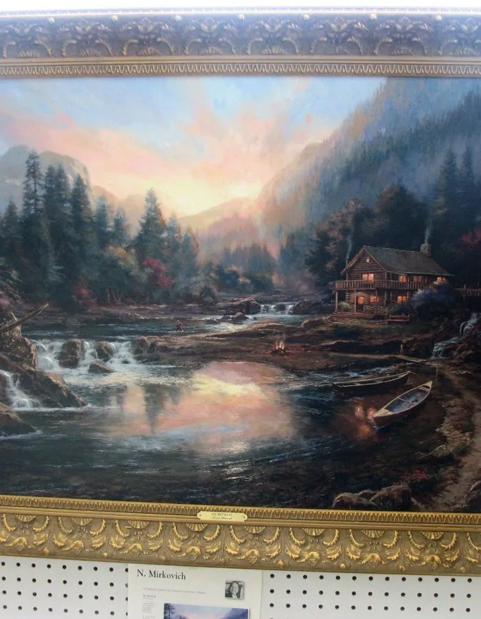 A landscape painting framed in a carved gold frame on display at One Price Framing in Chattanooga